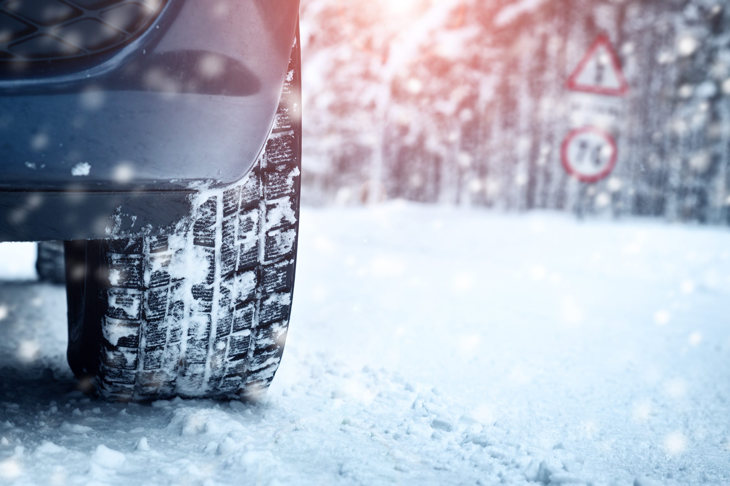 A photo of a car tire driving on a snowy road