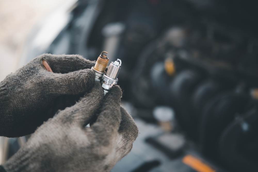 A photo of a mechanic holding two spark plugs