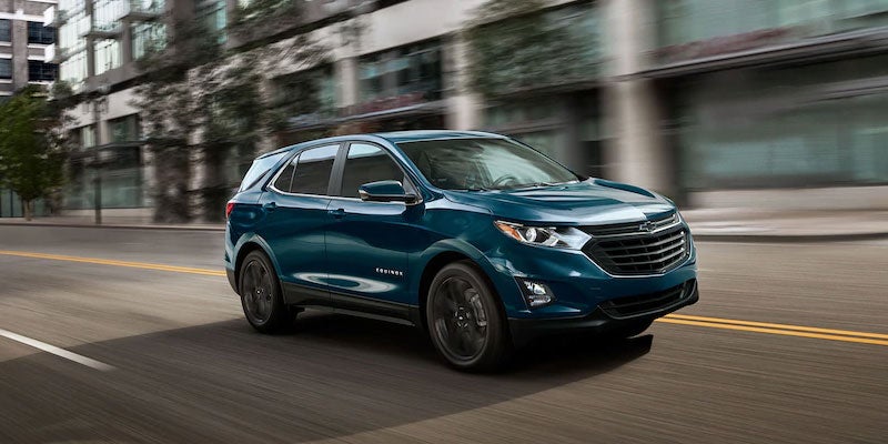 A photo of a blue 2021 Chevy Equinox driving down a city street.